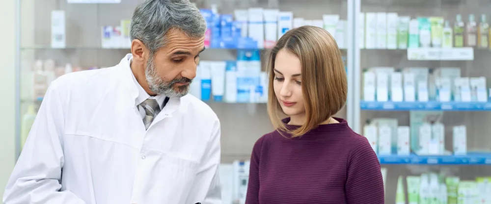 Flinders Discount Chemist | Free Health Checks in Flinders Pharmacist in a white coat going over a paper with a customer in front of pharmacy shelves